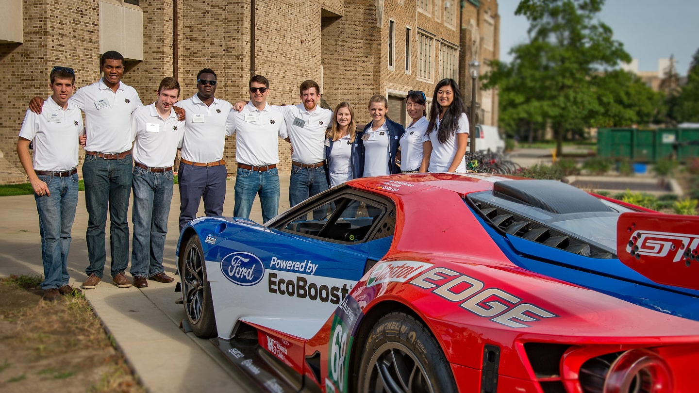 students in front of sports car