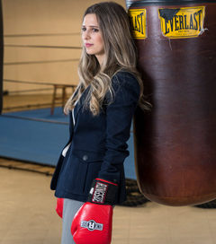 Gina Guzzardo in boxing gloves leaning against a punching bag