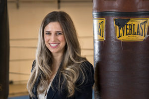 Student Gina Guzzardo smiling while leaning against a punching bag