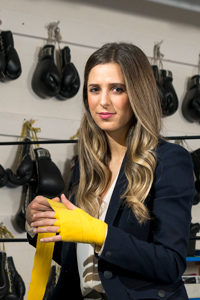 A woman wraps yellow boxing tape around her palms