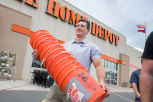 man carrying a stack of orange buckets from a Puerto Rico Home Depot