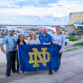 participants of the Business on the Front Lines program stand with an ND flag in front of waterfront in Brazil
