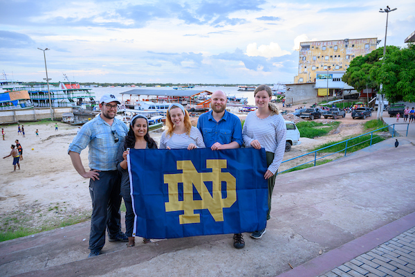 participants of the Business on the Front Lines program stand with an ND flag in front of waterfront in Brazil
