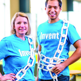 A man and a woman standing next to each other with blue invent t-shirts on and wearing white plastic chains