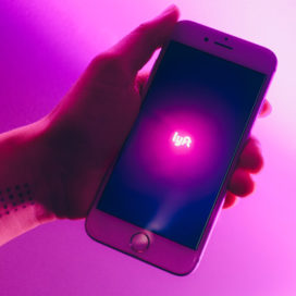 hand holding a cellphone with the lyft logo on it