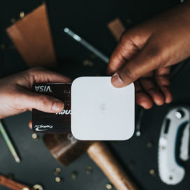 hands hold a credit card inside of a handheld wifi card reader