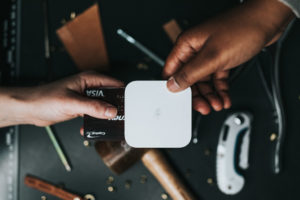 hands hold a credit card inside of a handheld wifi card reader