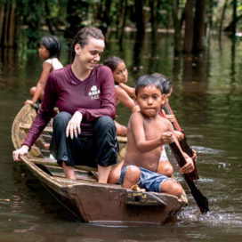 a woman rides in a canoe in the amazon with little children