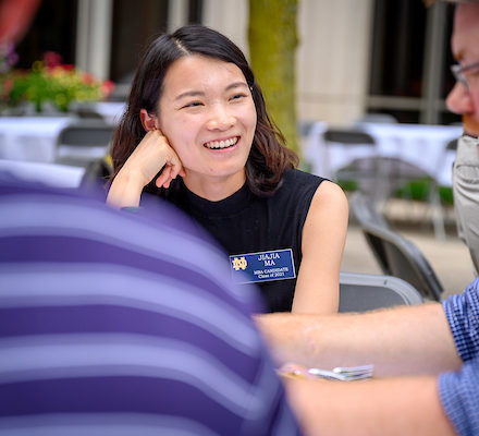 student smiling thoughtfully at a table outdoors