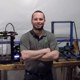 man stands in front of 3D printing equipment