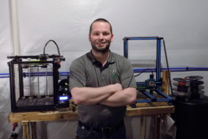 man stands in front of 3D printing equipment