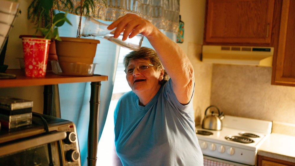 woman watering a plant in a kitchen