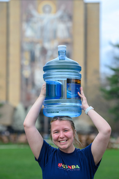 student holding water jug on her head