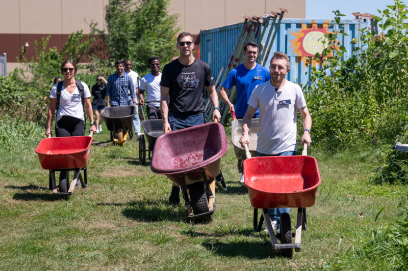 MBA students pushing wheelbarrows for a service project