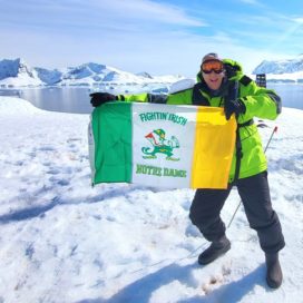 man holding an ND Irish flag in the mountains