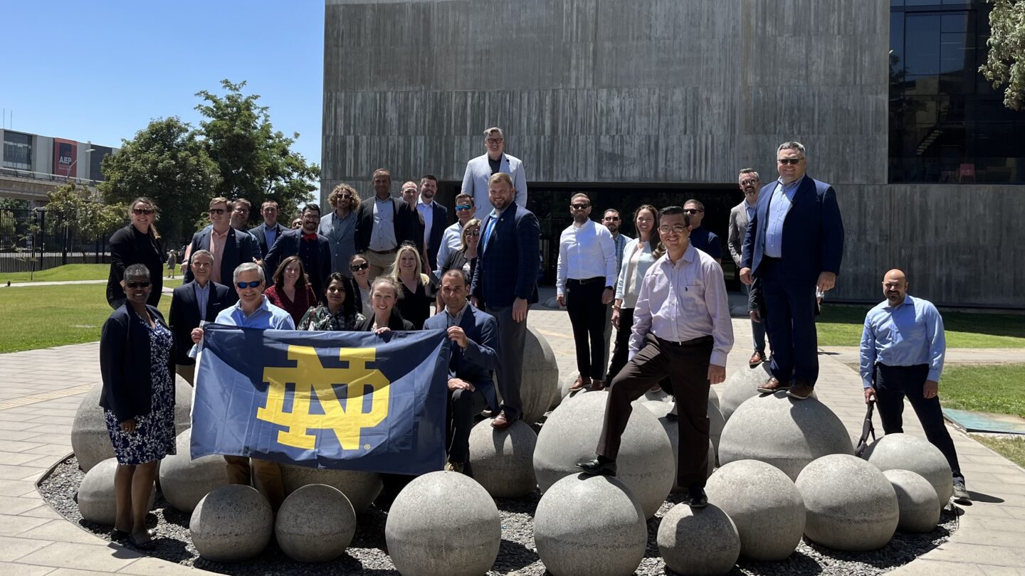 group of EMBA students in front of corporate office at international location holding an ND flag