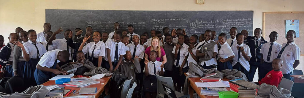 student standing with her class in Uganda