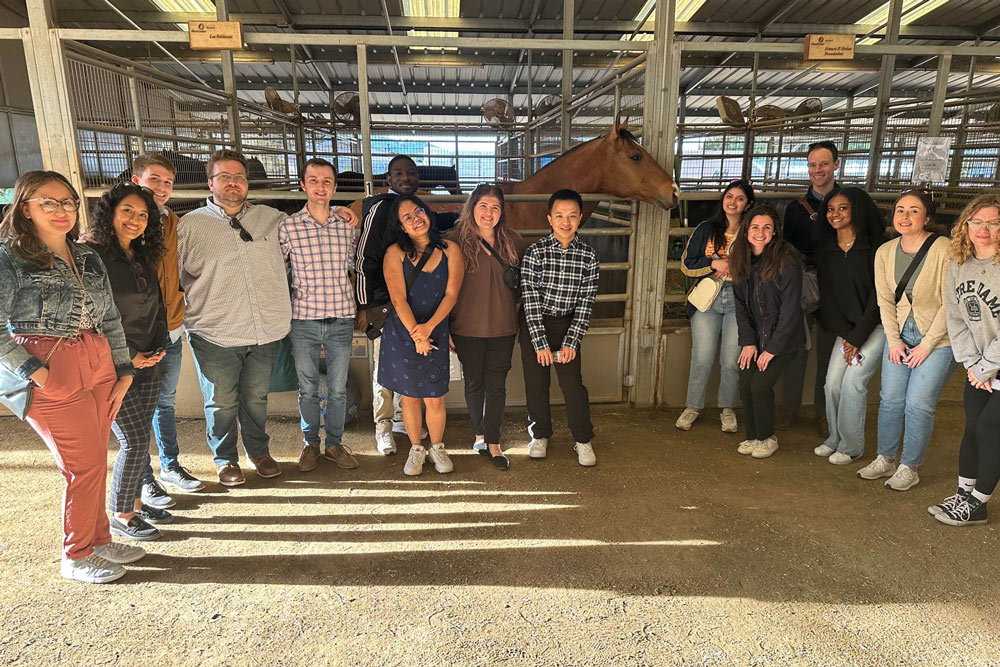 ND Business students pose in front of stable with horse