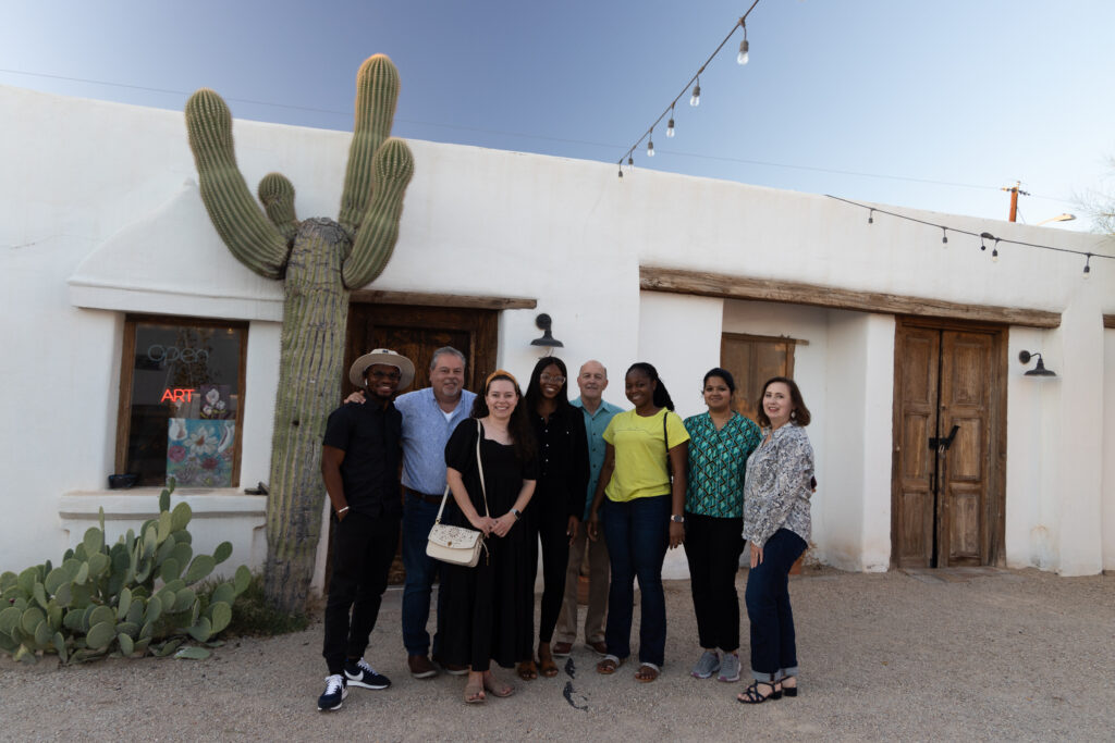 group of people standing outside a building with a cactus