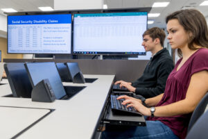 two students deeply focused in their work on built in desktop computers