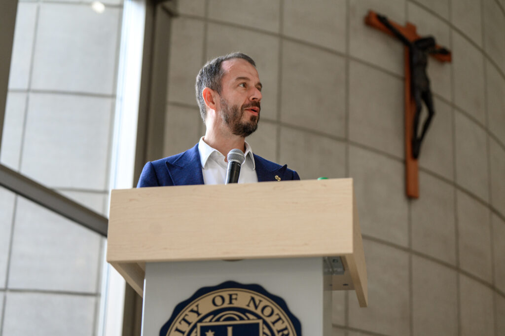 Dean Martijn Cremers speaking at a podium with a large crucifix in the background