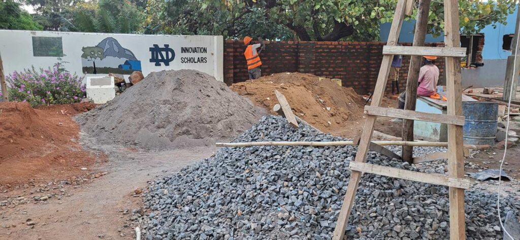 piles of building materials for the ECDC center in Uganda with a painted ND on a wall