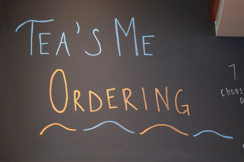a chalkboard sign with "tea's me ordering" written on it.