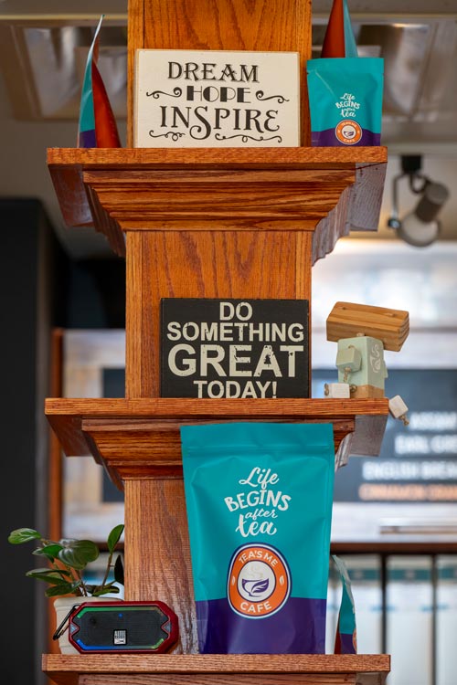 A shelf in Tamika Catching's tea shop with bags of tea and motivational signs.