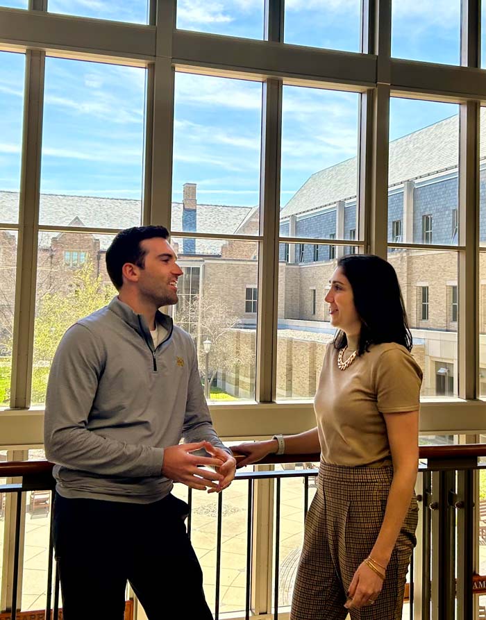 Brother and sister stand in front of the Mendoza windows.