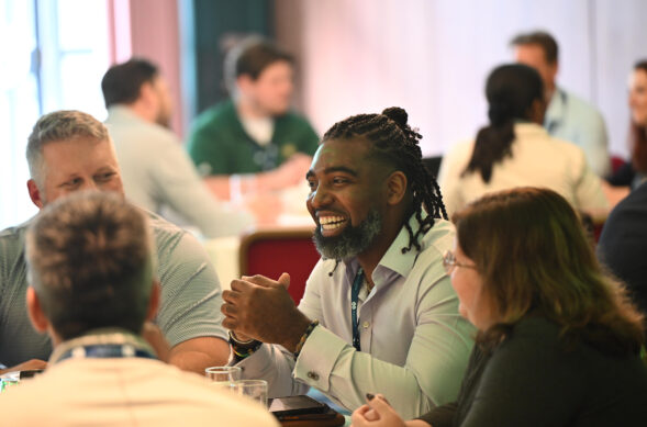 Executive MBA students sitting around a table during a leadership exercise smiling and engaged in group work.