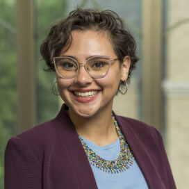 Headshot of female MBA stduent wearing a burgundy blazer and light blue blouse.