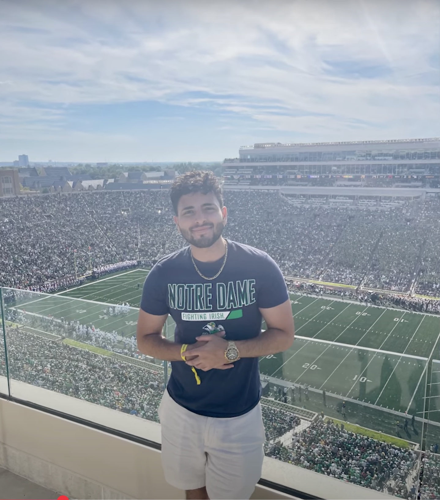Mark Metryoos stands in front of the Notre Dame Stadium with the football field in the background. 