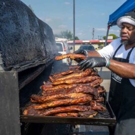 A man grills meat in a large outdoor oven.
