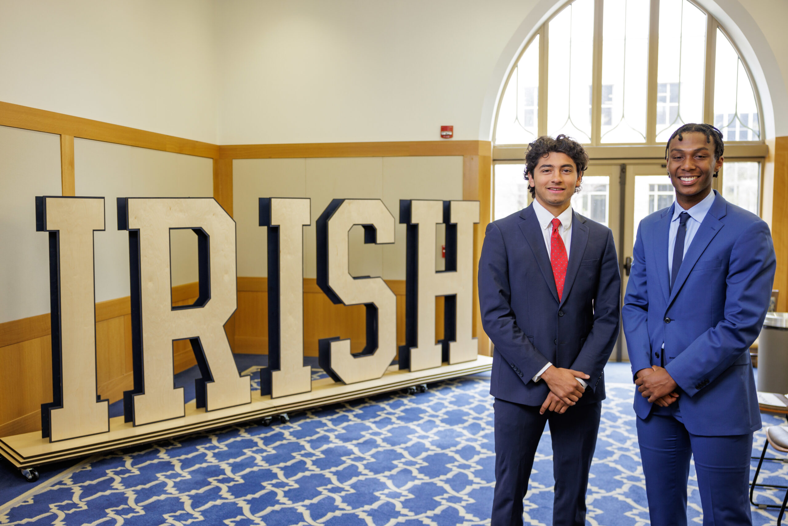 Cleveland Sellers IV poses with peer with wooden letters that spell out I-R-I-S-H in the background