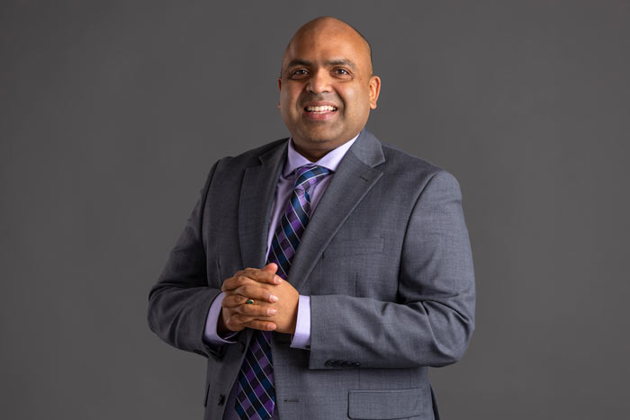 Sriram Somanchi smiles and holds his interlaced hands over his chest.