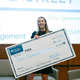 student holding an oversized check for winning the competition.