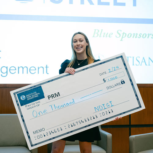 student holding an oversized check for winning the competition.