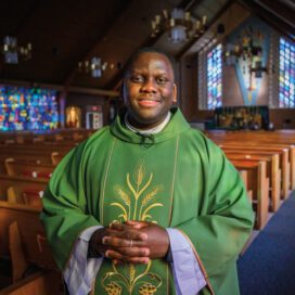 Arthur Joseph Ssembajja stands in his chapel smiling.